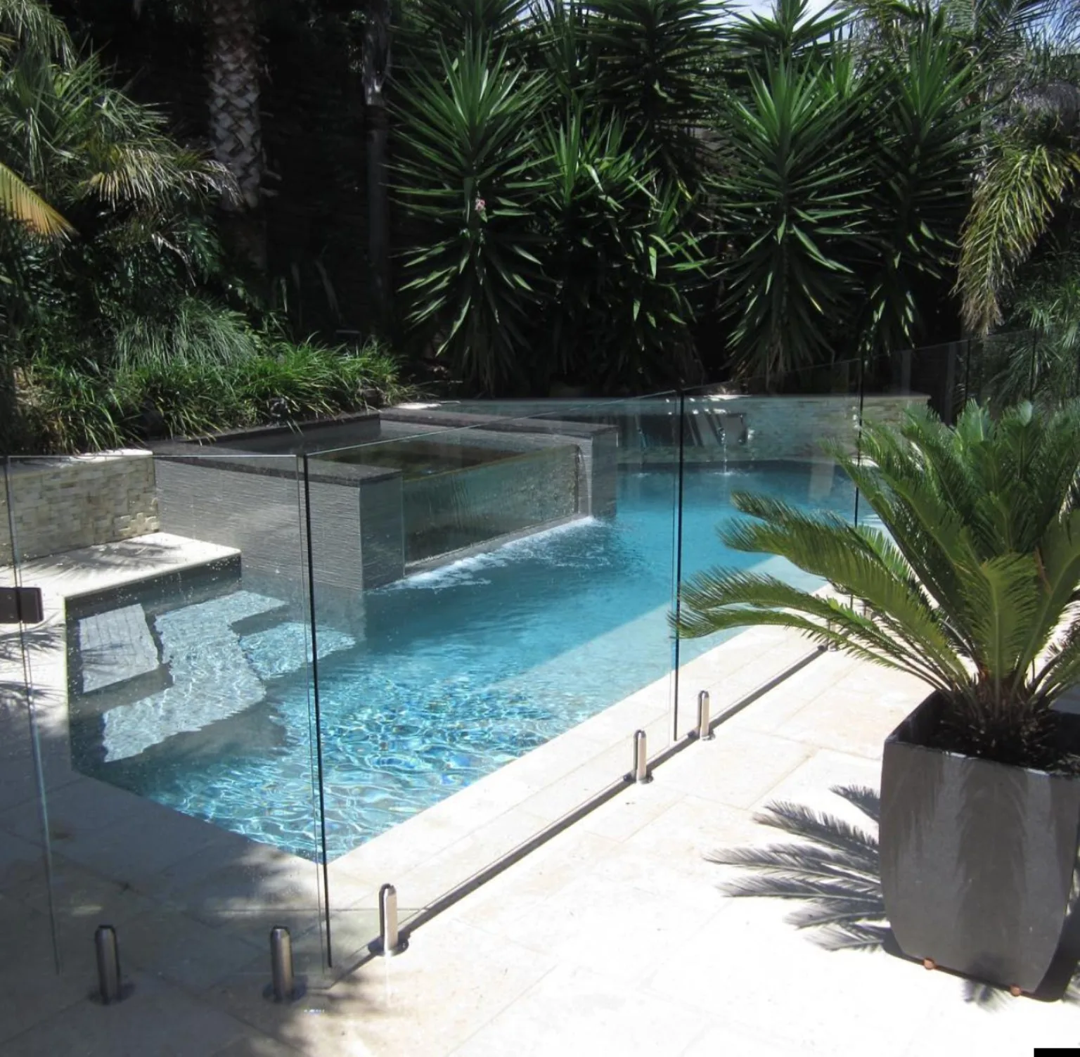 Instalación de cierre de vidrio alrededor de piscina residencial con terraza